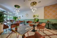 Un restaurante con mesas, sillas y lámparas de araña. en Urban Style Hotel Blason du Ventoux, en Carpentras