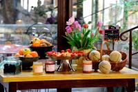 a table with bowls of fruit and baskets of flowers at The Originals Boutique, Hôtel du Parc, Cavaillon (Inter-Hotel) in Cavaillon