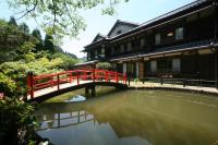 a red bridge over a pond in front of a building at Nanten-En in Kawachinagano