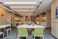 Un comedor con mesas blancas y sillas verdes. en Atour Hotel Hangzhou West Lake, en Hangzhou