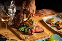 una persona cortando carne en una tabla de cortar con un cuchillo en MY ALPENWELT Resort, en Königsleiten