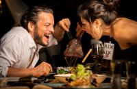 Un hombre y una mujer sentados en una mesa comiendo comida en MY ALPENWELT Resort, en Königsleiten