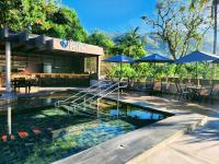 Una piscina con mesas y sombrillas frente a un hotel. en Minas Garden Hotel, en Poços de Caldas