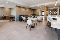 un restaurante con sillas y mesas blancas y un bar en Holiday Inn & Suites Columbia NE - Ft Jackson Area by IHG, en Columbia