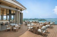 a restaurant with tables and chairs on a deck at The Westin Nirup Island Resort & Spa in Belakangpandang