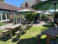 Un grupo de mesas de picnic y sombrillas en un patio. en The Kings Arms Inn, en Stockland