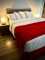 1 dormitorio con 1 cama roja y blanca y 2 lámparas en Aberdeen Motel, en Whycocomagh