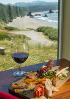 a plate of food and a glass of wine on a table at Redfish Rocks Villas - Green in Port Orford