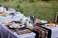 ein langer Tisch mit Tellern voller Essen darauf in der Unterkunft Pamoja Migration Camp in Serengeti-Savanne