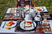 ein Tisch mit Tellern voller Essen auf einem Tisch in der Unterkunft Pamoja Migration Camp in Serengeti-Savanne
