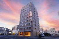 un edificio alto en una calle de la ciudad al atardecer en Dormy Inn Takasaki, en Takasaki