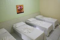 a room with three beds and a painting on the wall at JR Hotel in João Pessoa
