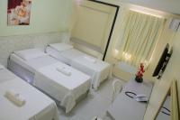 a hotel room with three beds and a television at JR Hotel in João Pessoa