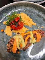 Un plato de comida con carne y un tomate encima. en Aquabella, en Aiguebelette-le-Lac