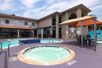 ein Swimmingpool mit Sonnenschirm neben einem Gebäude in der Unterkunft Ramada by Wyndham &amp; Suites South Padre Island in South Padre Island