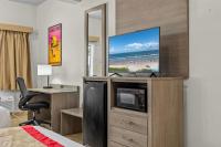 ein Hotelzimmer mit einem TV, einem Schreibtisch und einem Bett in der Unterkunft Ramada by Wyndham &amp; Suites South Padre Island in South Padre Island