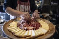 ARC 1600, LE RIDGE, Appartement 10 personnes Duplex Vue Montagne - ski aux pieds - Sauna, Hammam, Piscine, Salle de salle de sport-fitness في آرك 1600: شخص يقوم بإعداد الجبن واللحم على طبق