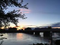 un ponte su un fiume con un tramonto sullo sfondo di Skyfall Guestrooms a Green River