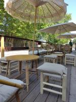 eine Holzterrasse mit Tischen, Stühlen und Sonnenschirmen in der Unterkunft Les copains d'amour in Guérande