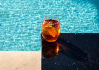 Happy Cretan Suites في أغيا بيلاغيا: مشروب موضوع على طاولة بجانب حمام السباحة