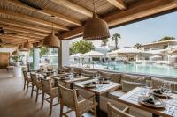 een eetkamer met tafels en stoelen en een zwembad bij AMĀRIA Beach Resort by NOMÉE Hospitality Group in Kamari