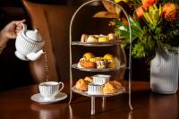 Una bandeja de tres niveles con pasteles y una taza de té. en Rydges South Bank Brisbane, en Brisbane