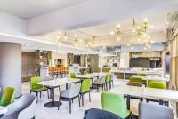 Atour Hotel Harbin Nangang District Government في هاربين: مطعم بطاولات بيضاء وكراسي خضراء