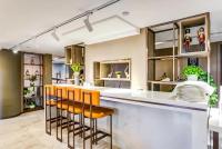 Atour Hotel Harbin Nangang District Government في هاربين: مطبخ مع بار مع كراسي برتقالية