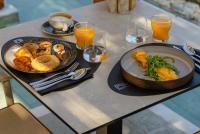 a table with two plates of food and two glasses of orange juice at Cabú Hotel - Adults Only in Faliraki