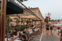 a group of people sitting at tables outside a restaurant at Pavillon Apartments in Peschiera del Garda
