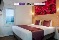 1 dormitorio con 1 cama grande con una pintura floral en la pared en Fasthotel Orleans Zénith, en Orléans