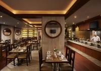 a restaurant with tables and a chef in the kitchen at Hotel The Royal Plaza in New Delhi