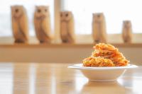 Un plato de comida en una mesa con gatos al fondo. en 別海まきばの湯しまふくろう, en Nishi-shumbetsu