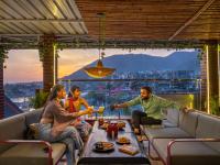 um grupo de três pessoas sentadas em um pátio com bebidas em The Hosteller Rishikesh, Ganges em Rishikesh