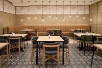 una sala da pranzo con tavoli, sedie e luci di Hyatt Place Montreal Airport a Dorval