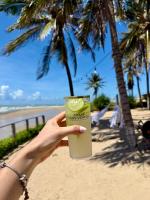 een hand met een drankje voor het strand bij Chalé dos Ventos in Amontada