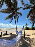 een hangmat op een strand met een palmboom bij Chalé dos Ventos in Amontada