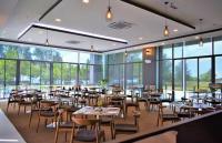 Un comedor con mesas y sillas y ventanas. en PD DWharf Hotel Suite & Serviced Residence, en Port Dickson