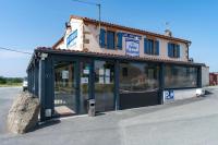 Un edificio con puertas de vidrio en un estacionamiento. en Hôtel La Petite Auberge, en Chambretaud