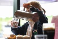 Uma mulher a derramar uma bebida num copo. em The Gables 