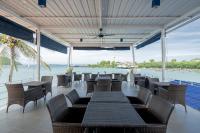 パナワビーチにあるPhuket Boat Quay Hotel Panwa Beachのテーブルと椅子が備わるレストランで、水辺の景色を望めます。