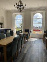 una sala da pranzo con tavolo, sedie e finestre di Lynton House Hotel a Teignmouth