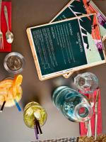 Una mesa con un menú y algunas bebidas y cubiertos. en Hôtel Amaya, en Ambarès-et-Lagrave