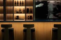 a bar with three bar stools in a room with wine bottles at AR Diamante Beach & SPA Hotel 4 SUP in Calpe