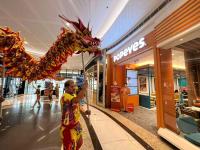 a woman holding a dragon statue in a shopping mall at Prime Location condo near MRT, SM Megamall, BGC! in Manila