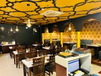 een restaurant met tafels en stoelen en een geel plafond bij Trimrooms Banaras Station in Varanasi