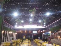 een restaurant met tafels en stoelen en een plafond met verlichting bij Hotel Oval in Surabaya