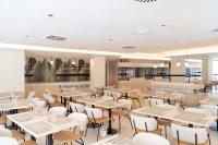 Un restaurante con mesas y sillas y un bar. en Hotel RH Arena - Todo Incluido, en Gandía