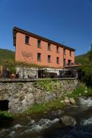 un edificio en una colina junto a un río en Tandem, en Vicdessos