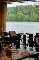 - un restaurant avec des tables et des chaises offrant une vue sur le lac dans l'établissement Esperanza Lake Resort, à Trakai